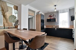 Eine moderne Küche mit Holzschränken, einem Esstisch mit Stühlen und einem an der Wand befestigten Fahrrad.