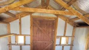 A rustic wooden barn interior with a central door, wooden beams, and insulated walls. - South Cabins - Private Island (Perth County)