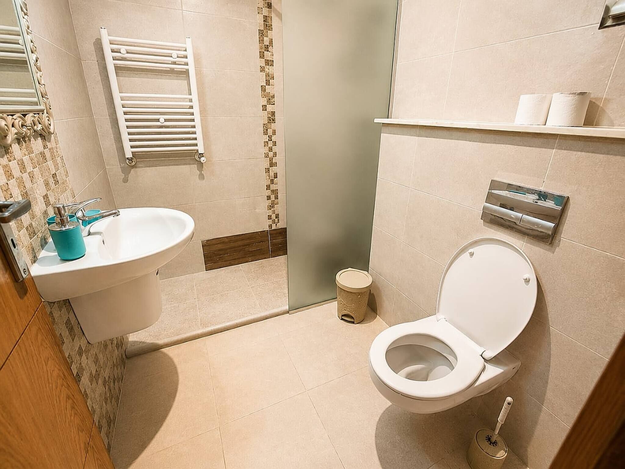Ein Badezimmer mit Waschbecken, Toilette, Handtuchhalter und Mülleimer.
