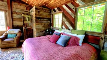 Een houten slaapkamer met een bed, een stoel en een raam.