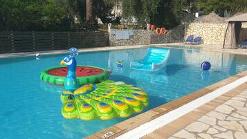 En swimmingpool med oppustelige vandlege, liggestole og en stenvæg.