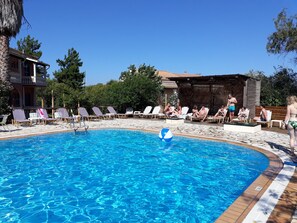Uma piscina com espreguiçadeiras e um deck de madeira.