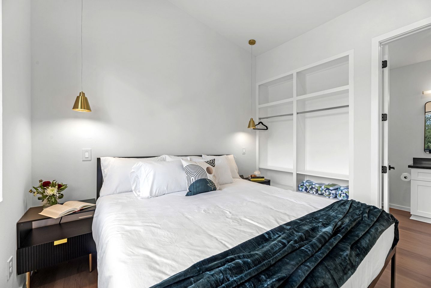 Une chambre à coucher moderne, comprenant un lit, des tables de chevet, une commode, une fenêtre et une porte.