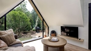 A modern living room with a large skylight, a TV, and a cozy seating area. - Blissful A-Frame Retreat near Pisgah National Forest in North Carolina (Balsam Grove)