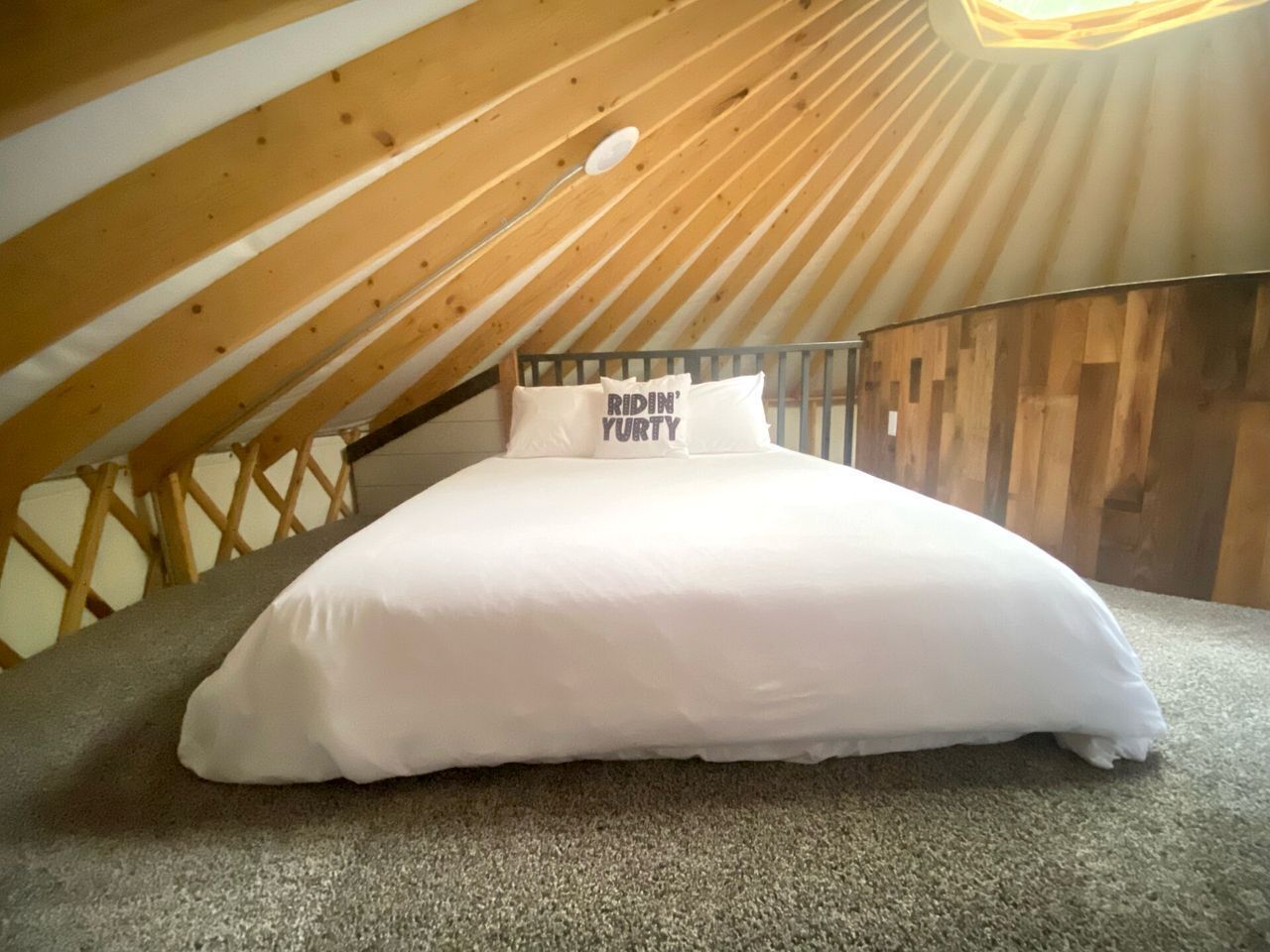 Un lit dans une chambre située sous les combles, avec un plafond en pente et des poutres en bois.