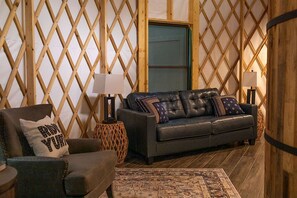 Una sala de estar acogedora con un sofá de cuero, un tapete estampado y una pared de celosía de madera.
