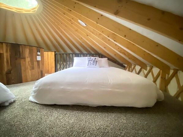 Una cama individual en una habitación con techo inclinado y vigas de madera.