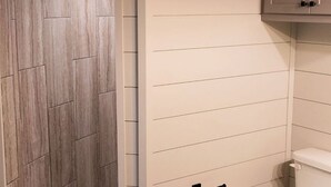 A bathroom with a shower, toilet, and wooden flooring.
