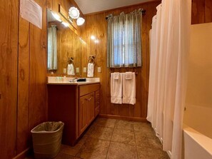 Un baño de madera con un lavamanos, espejo y dos toallas colgadas en un perchero.