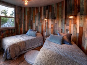Ein Zimmer mit zwei Betten, Holzwänden und einem Fenster.