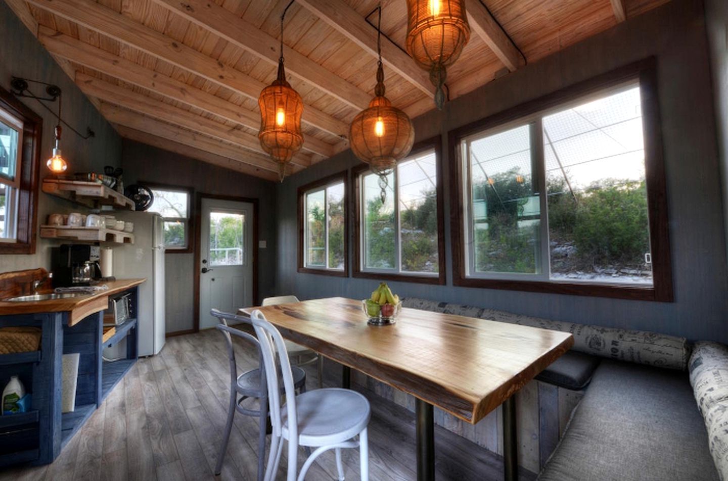A kitchen with wooden cabinets, a dining table, and hanging light fixtures.