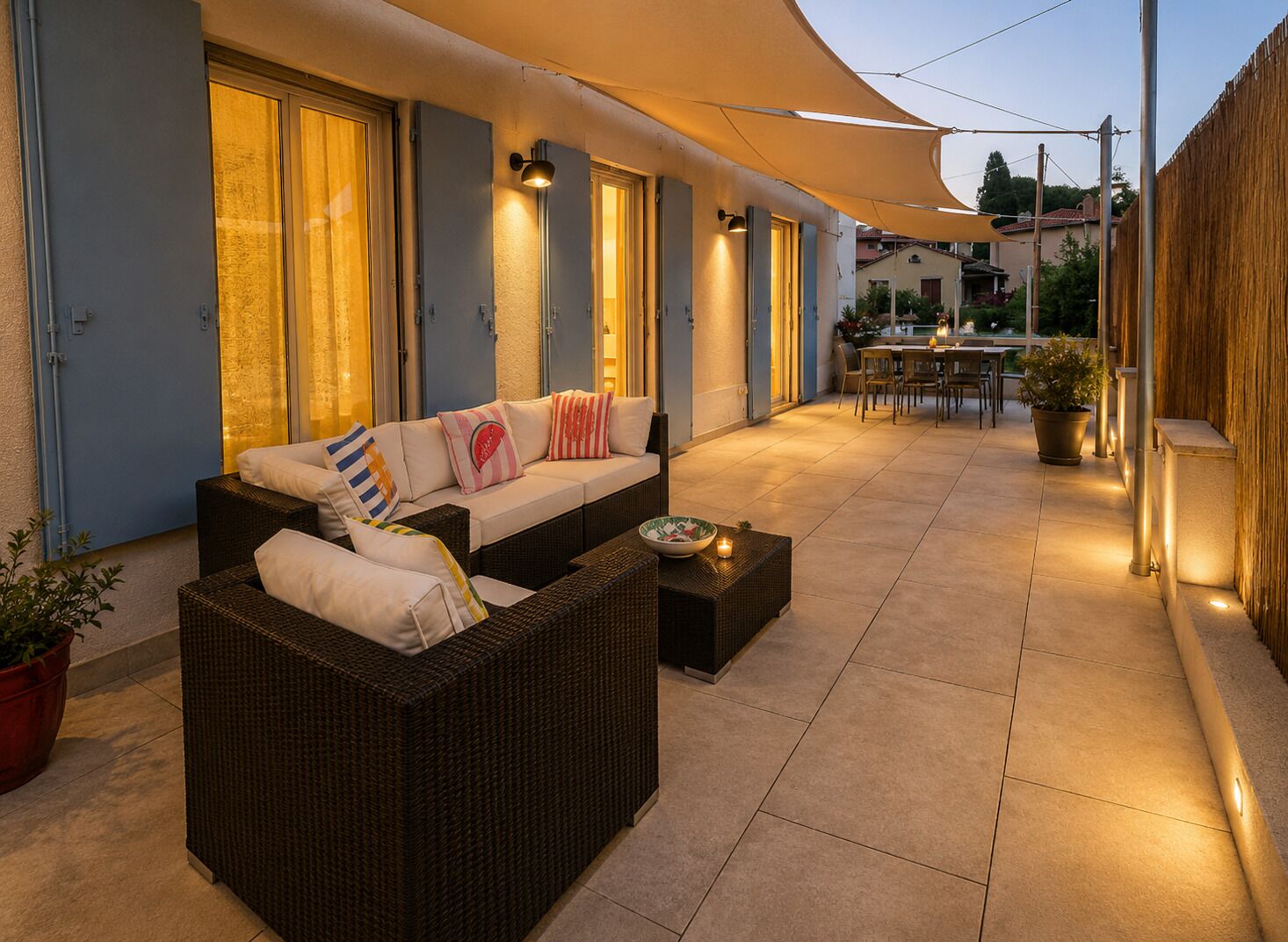 An outdoor patio area with a sofa, dining table, and chairs, under a canopy.