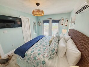 Une chambre à coucher avec un lit, une télévision, un ventilateur de plafond et une vue sur l’extérieur.