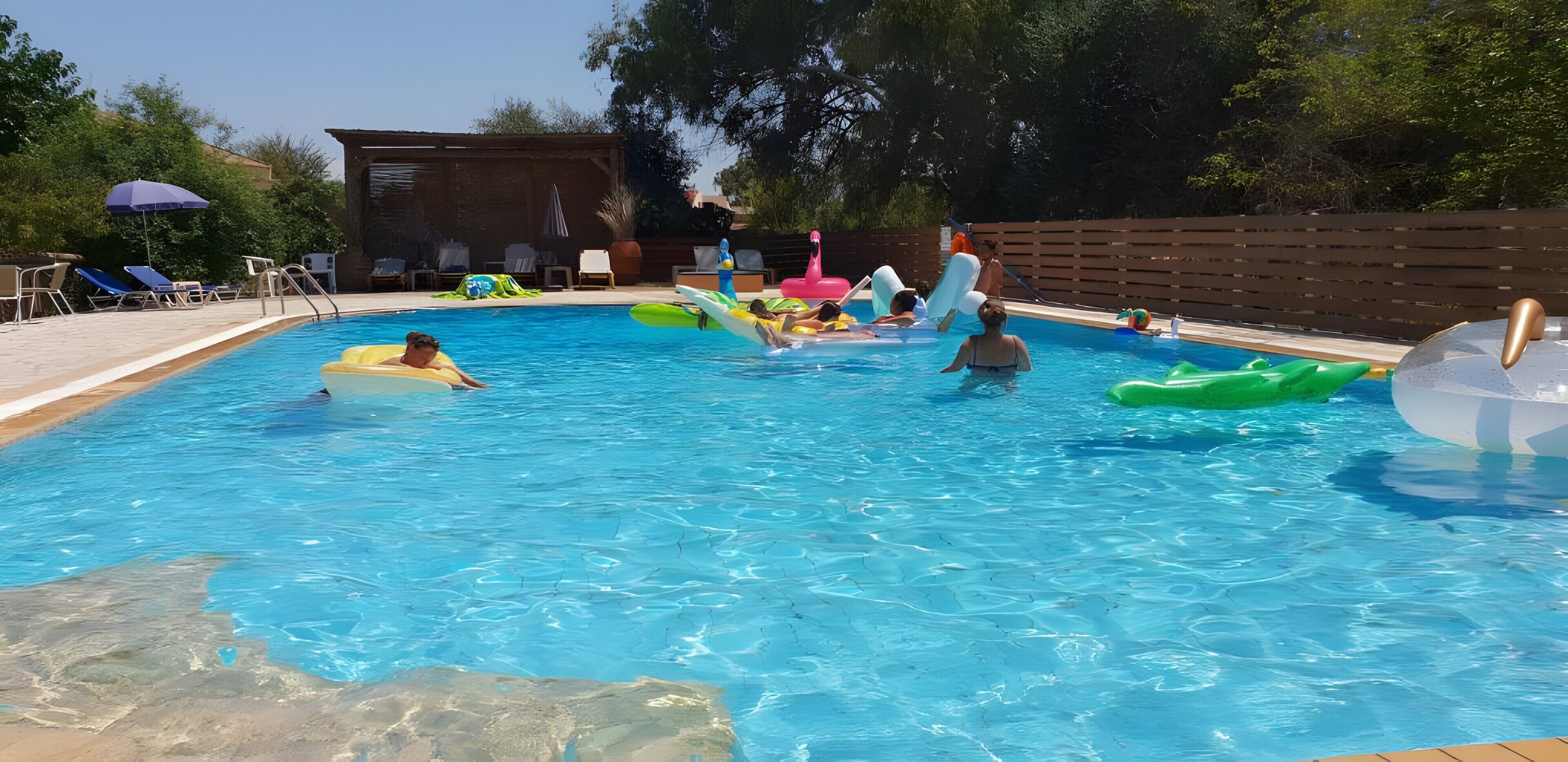A swimming pool with lounge chairs and inflatable toys.