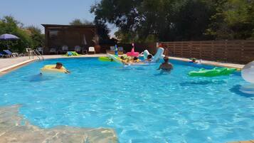 A swimming pool with lounge chairs and inflatable toys.