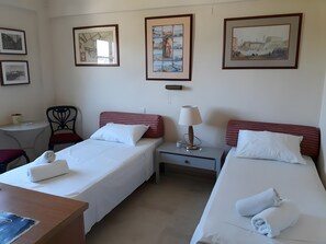 Een hotelkamer met twee bedden, een tafeltje, een stoel en wandelingen met afbeeldingen.
