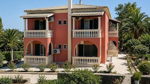 Un immeuble à plusieurs étages, doté de balcons, de fenêtres en arc de cercle et d’un toit recouvert de tuiles.