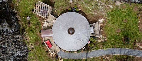 Een rond gebouw met een centrale koepel, omgeven door een terras en een klein gebouwtje met een rode dakbedekking.