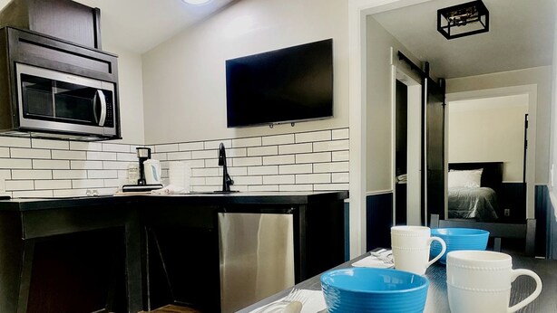 A modern kitchen with a microwave, a flat-screen TV, and a dining area with blue and white bowls.