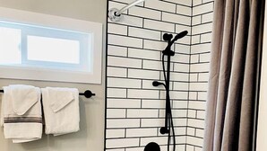 A bathroom with a bathtub, shower, and a window.