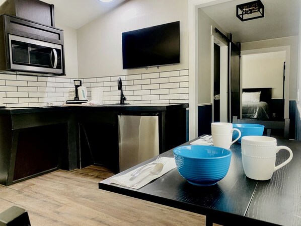Cocina moderna con microondas, televisión de pantalla plana y comedor con cuencos azules y blancos.