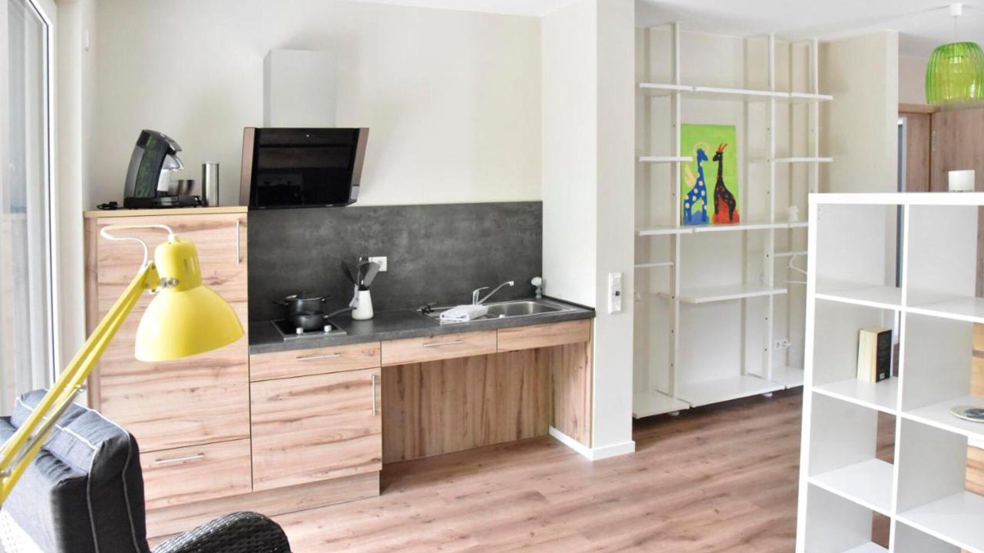 Une cuisine moderne avec des meubles en bois, une cuisinière encastrée et une lampe de bureau jaune.
