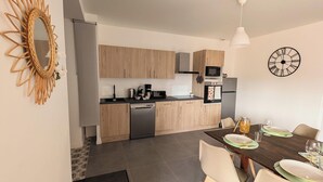 Une cuisine moderne avec des meubles en bois, un four encastré et un coin repas avec une table dressée pour deux personnes.