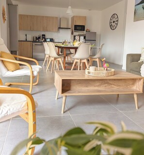 Ein modernes Wohnzimmer mit einem Holztisch, weißen Stühlen und einem Essbereich mit Holztisch und -stühlen.