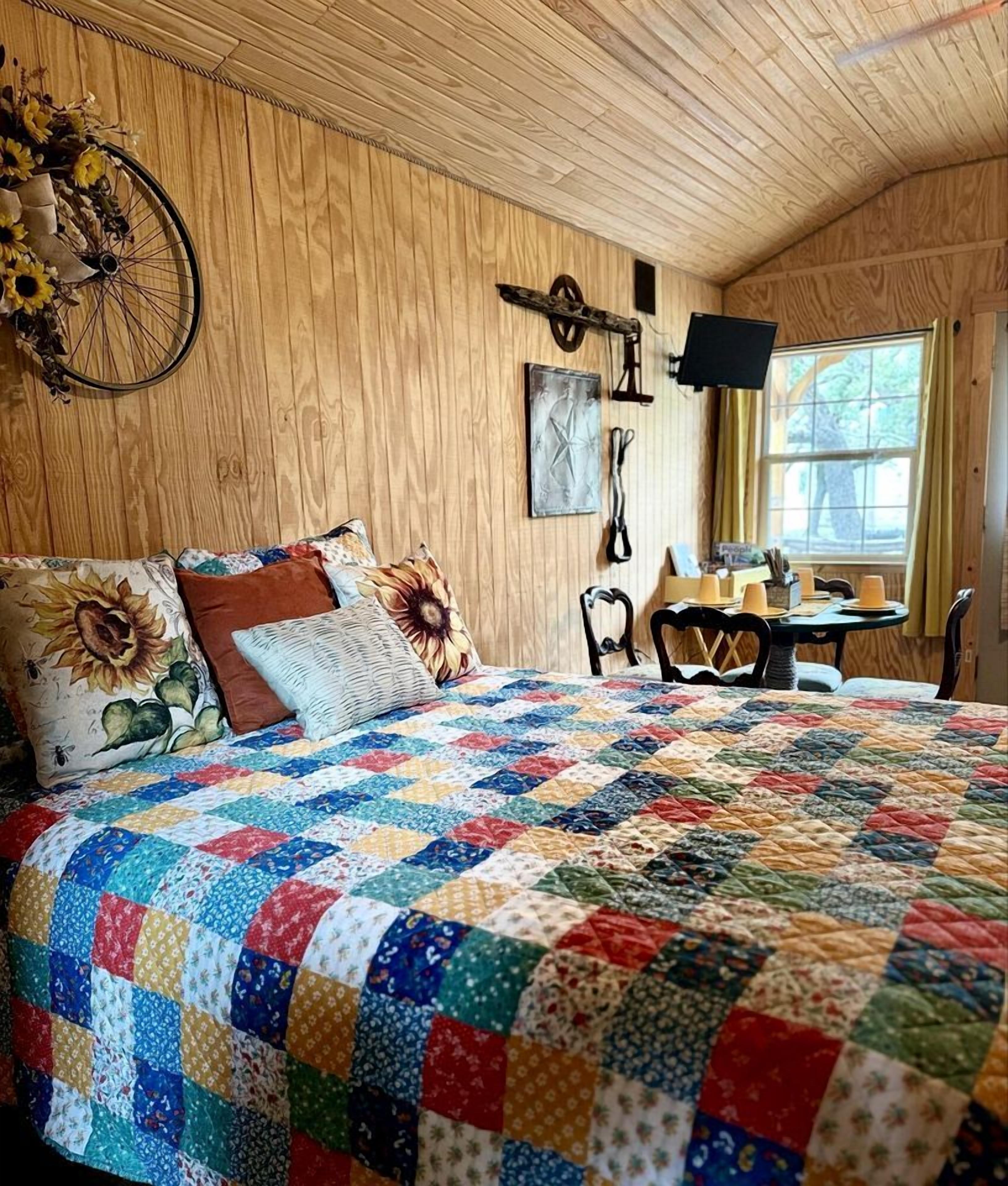 Ein Zimmer mit Holzwänden, einem großen Bett, einer Fahrraddekoration, einem Tisch mit Stühlen und einem Fenster.