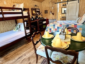 Una habitación acogedora con literas, una mesa de comedor con platos y velas, y una zona de cocina.