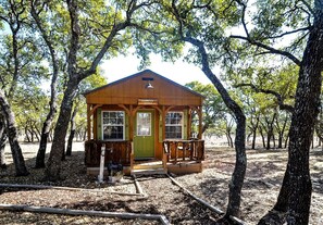 A small wooden cabin labeled 'CARRIAGE HOUSE' surrounded by trees. - Cozy Western-Style Cabin with Dark-Sky Stargazing near Mountain Home, Texas (Mountain Home)
