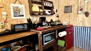 A rustic kitchen with wooden walls, a wooden countertop, a red refrigerator, and a microwave.