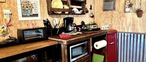 Een landelijke keuken met houten wanden, een houten aanrecht, een rode koelkast en een magnetron.