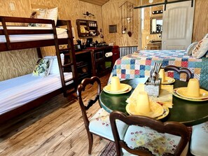 A cozy room with bunk beds, a dining table with plates and candles, and a kitchen area. - Cozy Western-Style Cabin with Dark-Sky Stargazing near Mountain Home, Texas (Mountain Home)