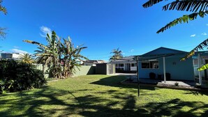 A residential backyard with a house, a fenced area, and tropical vegetation. - One Bedroom Blue Horizon close to everything (Tuncurry)