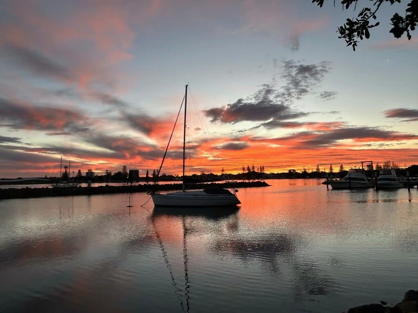 Ruhiges Ufer bei Sonnenuntergang mit einem vor Anker liegenden Segelboot in der Nähe des Strandes.