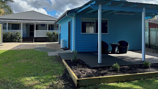 A blue house with a porch, a small garden, and a neighboring house. - One Bedroom Blue Horizon close to everything (Tuncurry)