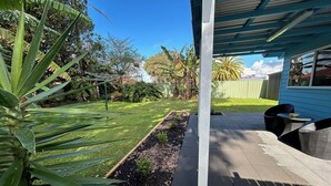 A patio area with a covered seating area, a garden with various plants, and a fence in the background. - One Bedroom Blue Horizon close to everything (Tuncurry)