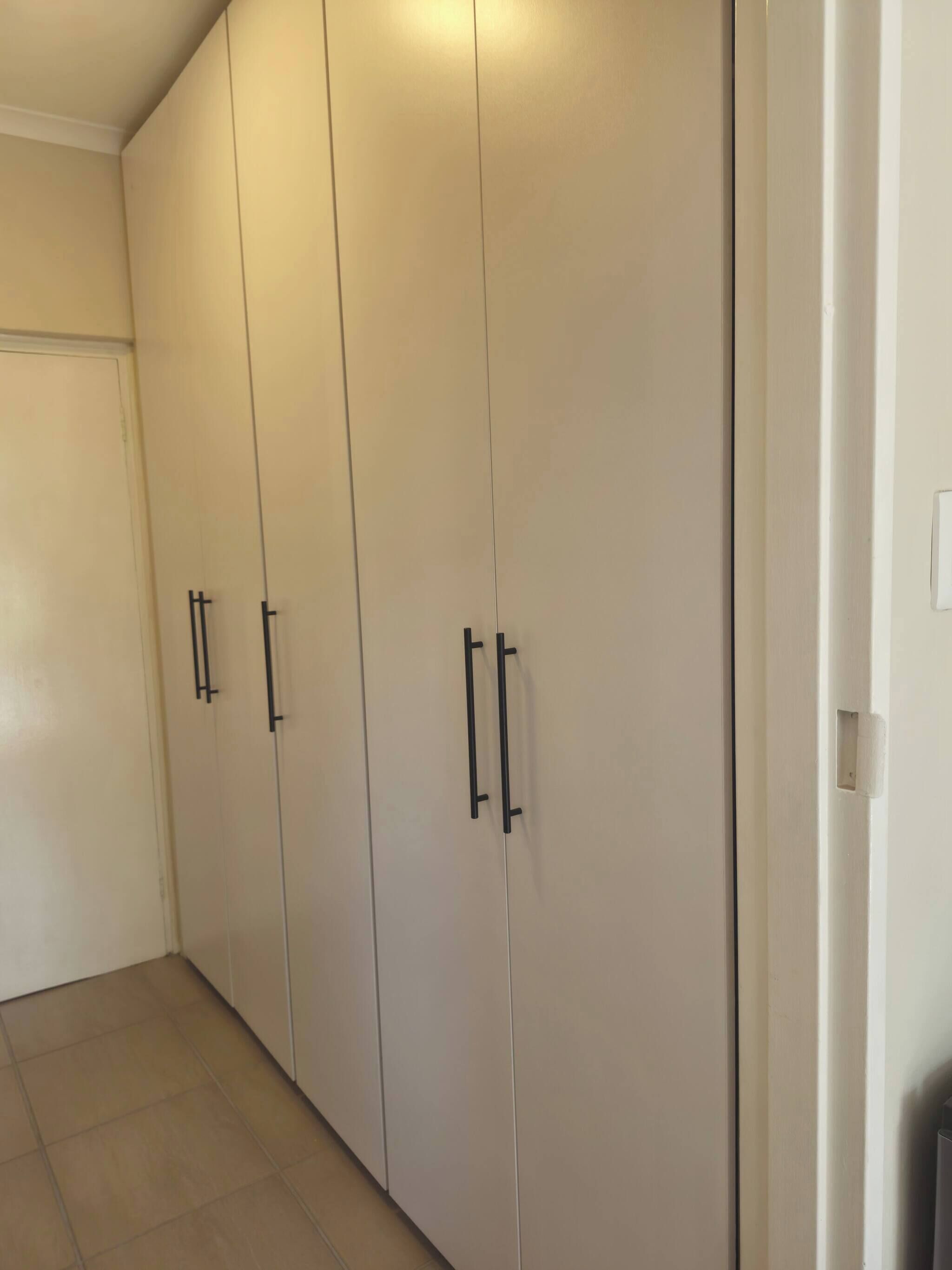 A hallway with a large wardrobe, a door, and tiled flooring.