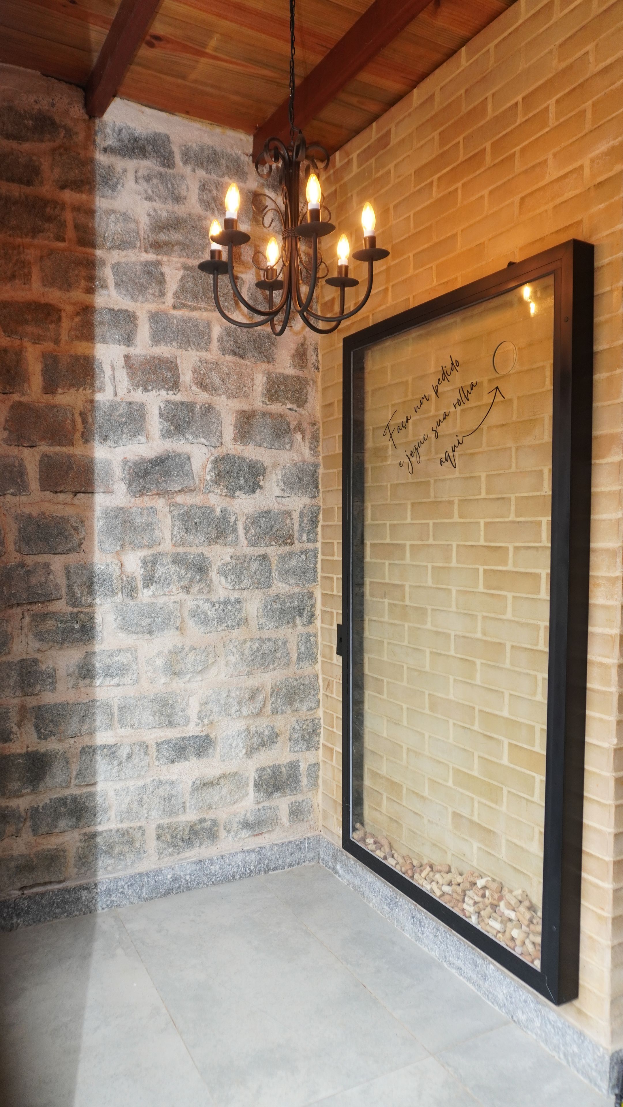 Una habitación con pared de piedra, techo de madera y candelabro.