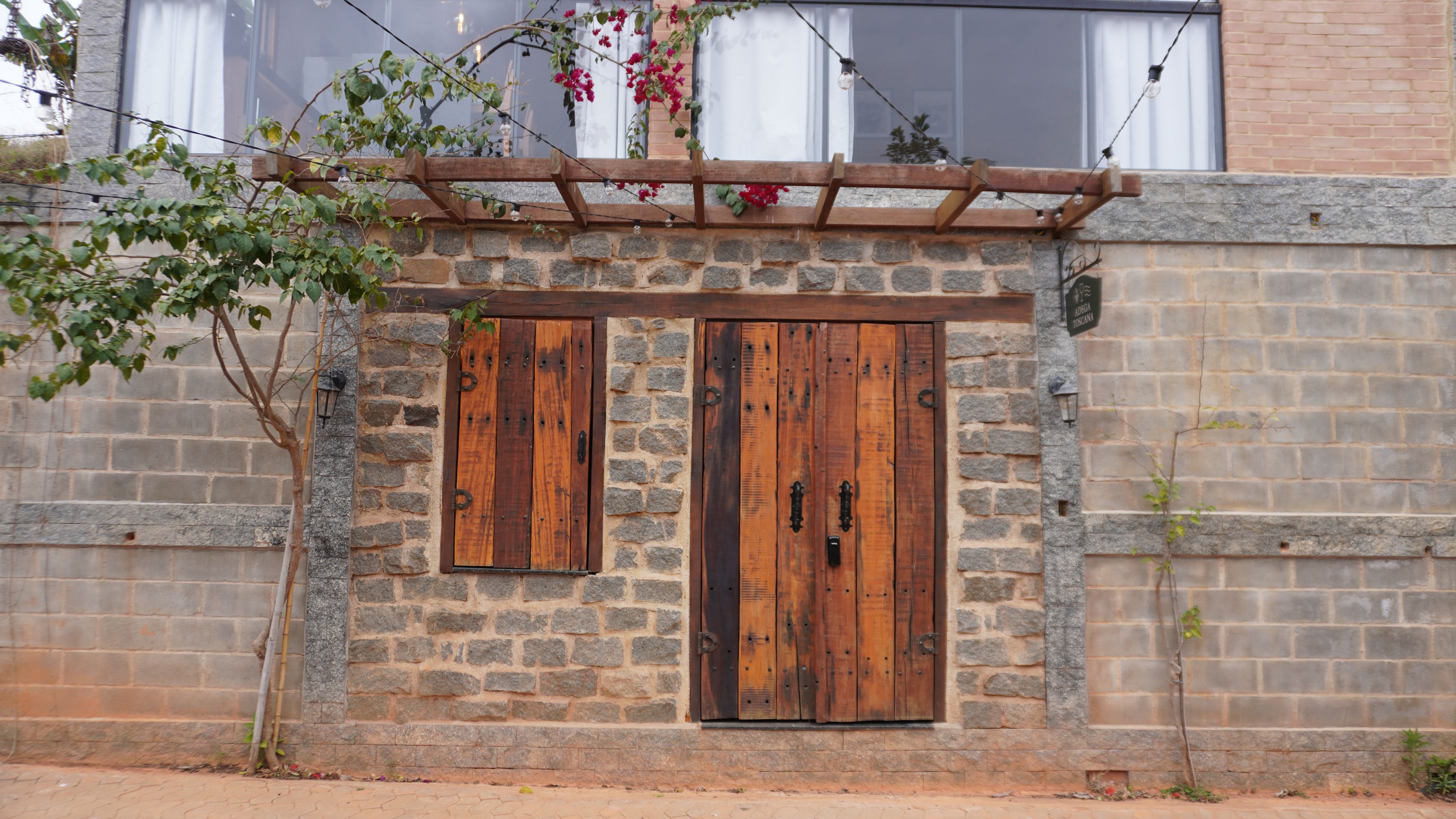 A stone wall with a wooden door and window, a small plant, and a string of lights.