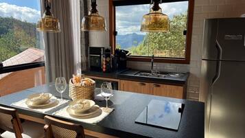 Una cocina con una isla grande, un refrigerador y un ventanal con vistas a la montaña.