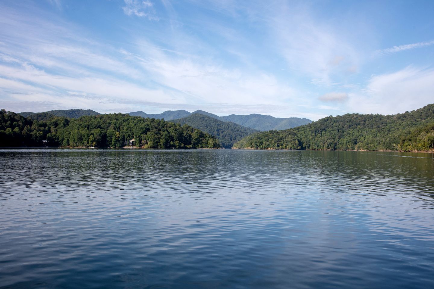 A calm lake with forested hills in the background.