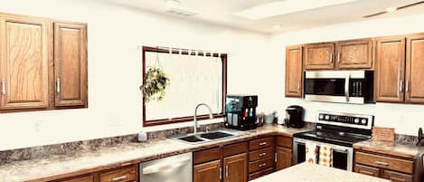 A modern kitchen with wooden cabinets, stainless steel appliances, and a granite countertop.