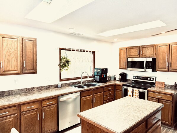 A modern kitchen with wooden cabinets, stainless steel appliances, and a granite countertop.