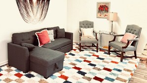 A living room with a sofa, two armchairs, a coffee table, a patterned rug, a wall hanging, and a framed picture. - Cozy Portage Lakes Hideaway (Akron)