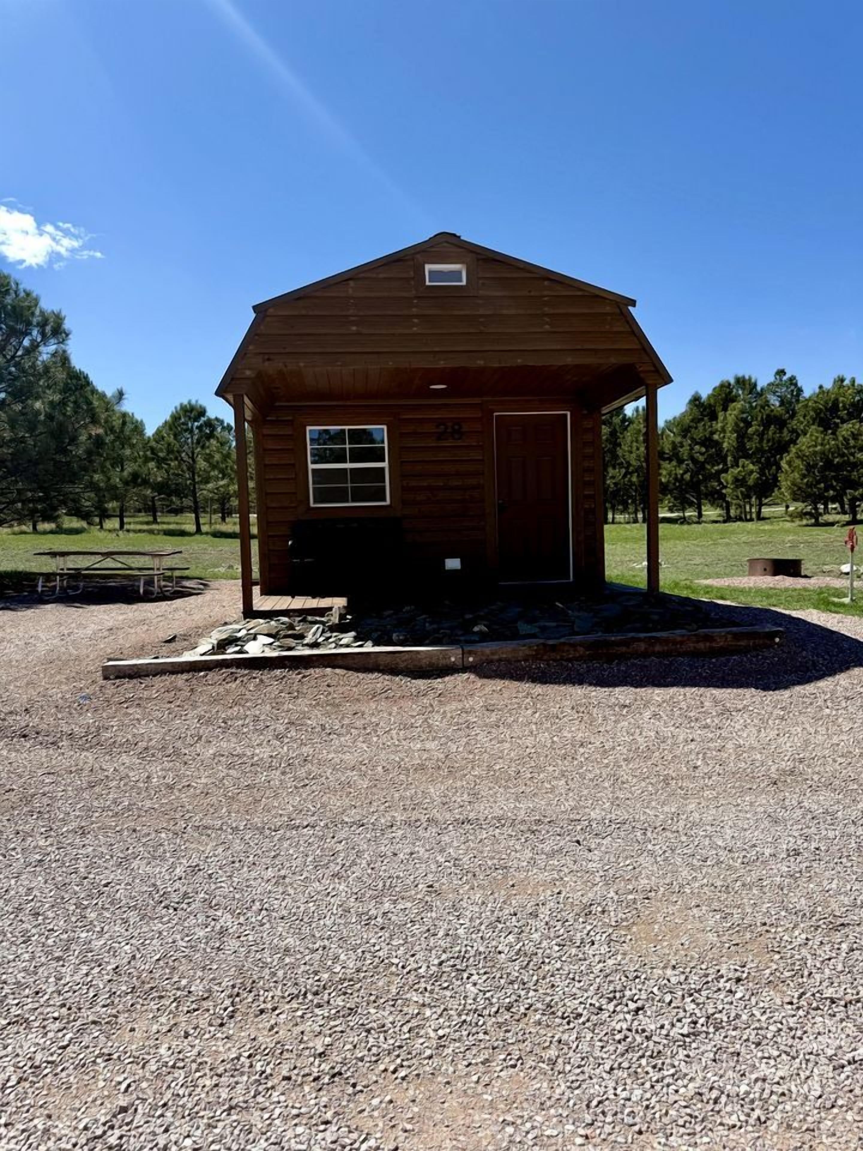 A wooden cabin with a porch, a door, and a window.