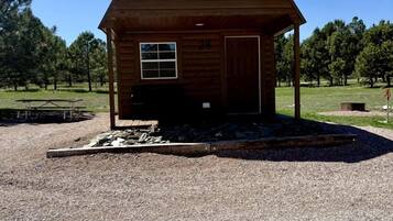 A wooden cabin with a porch, a door, and a window.
