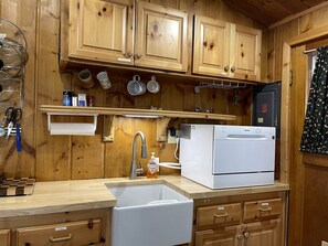 A kitchen with wooden cabinets, a white refrigerator, a sink, and various kitchen utensils. - Cozy Secluded Cabin Surrounded by Trees near Yellowstone, Idaho (Island Park)