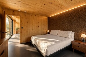A bedroom with a large bed, wooden walls, and a view through an open door. - Contemporary Forest Hideaway with Stunning Glass Architecture in Tracy, Tennessee (Tracy City)